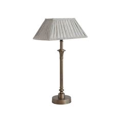 a lamp that is sitting on top of a white table cloth covered flooring with a beige pleated lampshade