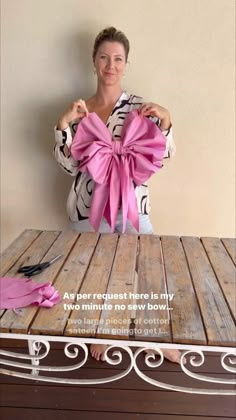 a woman sitting at a table with a pink bow on it