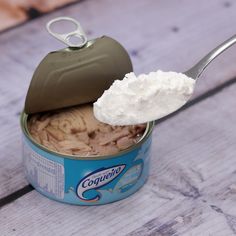 a spoon full of ice cream sitting in a can on top of a wooden table