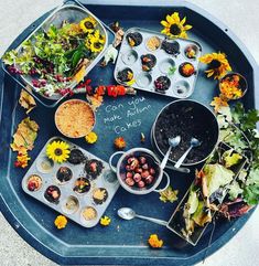 a tray filled with muffins and flowers on top of a blue tablecloth