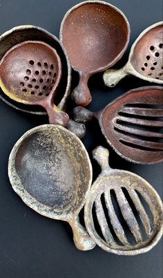 an assortment of old metal utensils on a black surface with holes in them