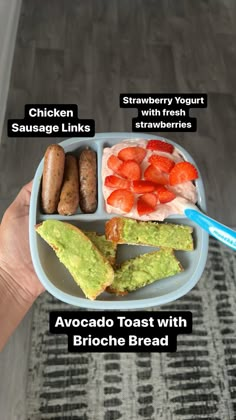 a person holding a plate with different types of food on it, including strawberries, sausage links, avocado toast and broccoli bread