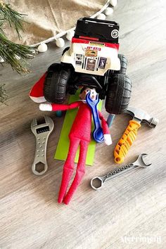 an elf is laying on the floor next to some tools and a toy monster truck