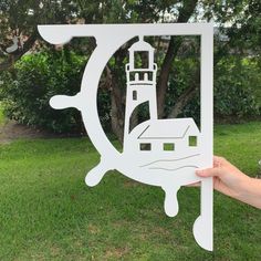 a hand holding up a cutout of a lighthouse