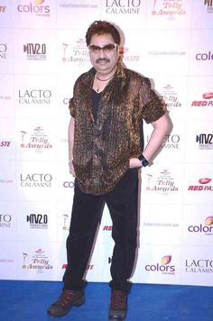 a man standing on top of a blue carpet wearing black pants and a brown shirt