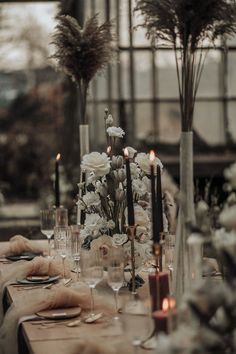 the table is set with candles, flowers and wine glasses for an elegant dinner party