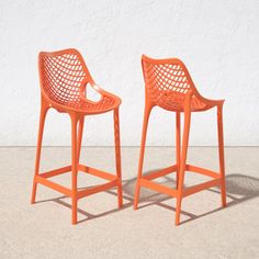 two orange plastic chairs sitting next to each other