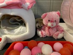 a pink teddy bear sitting next to an egg crate and other stuffed animals on a table