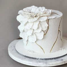 a white hat with flowers on it sitting on a marble plate next to a gray wall