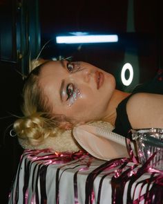 a woman laying on top of a bed covered in makeup