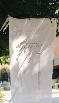 a large white sign hanging from the side of a tree