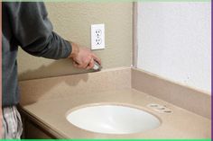 a person is using a hand dryer on a bathroom counter top with a white sink