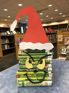 a stack of books sitting on top of a table covered in santa's hat