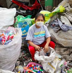 a woman sitting on the ground surrounded by garbage