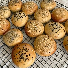 several sesame seed bagels cooling on a wire rack with black sprinkles