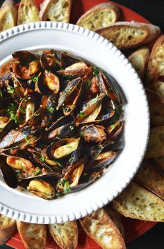 a plate full of mussels with bread in the background