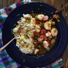 a blue plate topped with shrimp, rice and veggies next to a wooden table