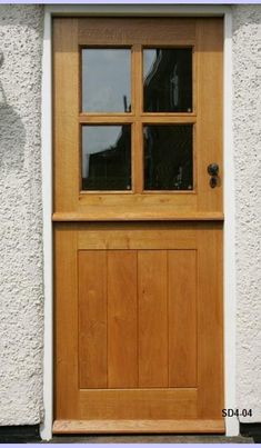 a close up of a wooden door on a white building with glass paned windows