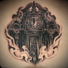 a clock tattoo on the back of a man's shoulder with flames coming out of it