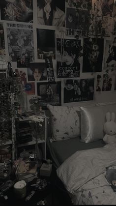 an unmade bed with many pictures on the wall above it and a teddy bear