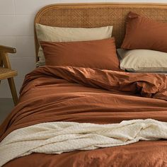 an unmade bed with brown sheets and pillows