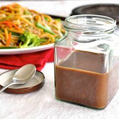 a glass jar filled with brown liquid next to a plate of food