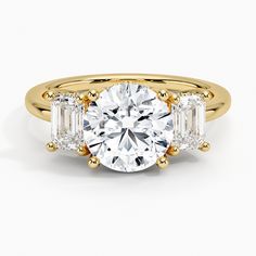 a three stone engagement ring with two baguets in yellow gold and white diamonds