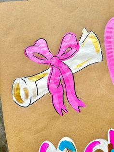 some paper plates and pink ribbon on top of a piece of brown paper with scissors