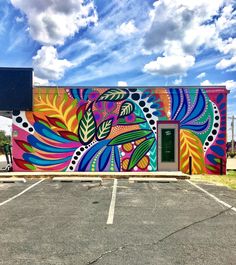 a colorful painted building with a green door in the parking lot and blue sky behind it