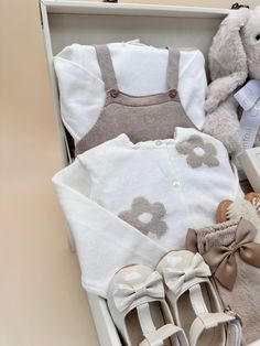 a baby's gift box with shoes, sweaters and teddy bear in it