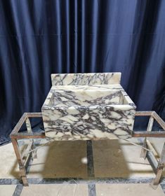 a marble coffee table sitting on top of a tile floor next to a blue curtain