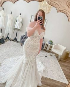 a woman taking a selfie in front of a mirror wearing a white wedding dress