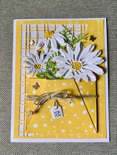 a yellow and white card with daisies on the front, tied in twine