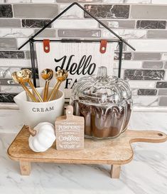 a wooden tray topped with jars and spoons next to a sign that says hello fall