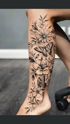 a woman's leg with flowers and butterflies on it, while she has her legs tattooed