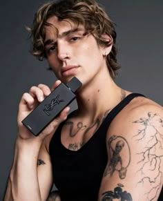 a young man with tattoos holding an electronic device