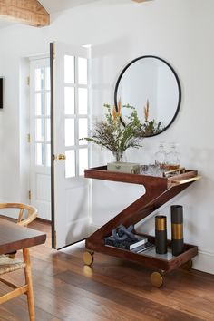 a living room with a table, mirror and vases on it's shelf