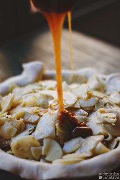 an orange sauce being poured on food in a bowl