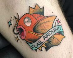 a man with a tattoo on his leg has an orange fish in it's mouth