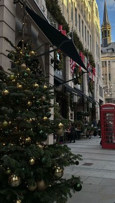 a christmas tree in the middle of a city street with a red phone booth on it