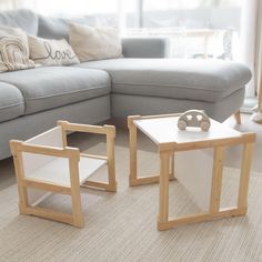 two small wooden tables sitting on top of a rug next to a gray couch in a living room