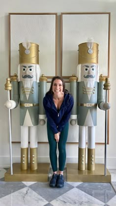 a woman standing in front of two nutcrackers with their hands on the ground