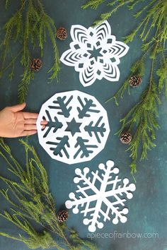 snowflakes and pine cones are cut out from the paper to make christmas decorations