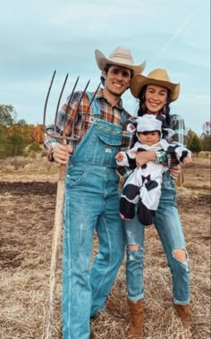 a man and woman in overalls holding a baby