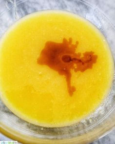 an orange substance is in the middle of a glass bowl on top of a marble table