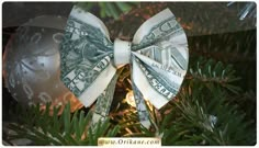 a bow made out of money sitting on top of a christmas tree