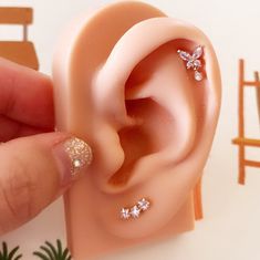 someone is holding their fake ear to show it's tiny diamond studded design