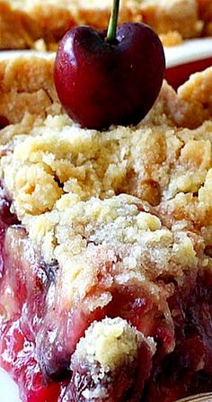 a piece of cherry pie on a plate with a fork and cherries in the background