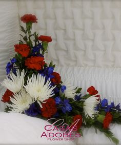 red, white and blue flowers are arranged in a bouquet on top of a bed