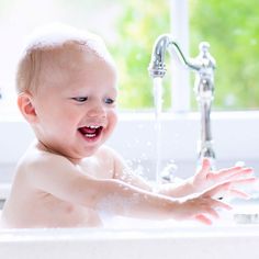 a baby is playing in the sink with water coming out of it's mouth